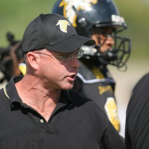 Football coach passionately motivating his team during a game.